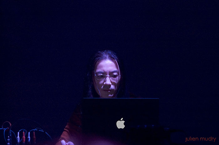 Merzbow assis derrière un de ses ordinateurs.