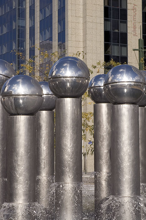 Une fontaine métallique et brillante, composée de sphères au sommet de mâts.