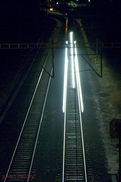 Les trois phares avant d'une locomotive, fonçant à vive allure en pleine nuit.